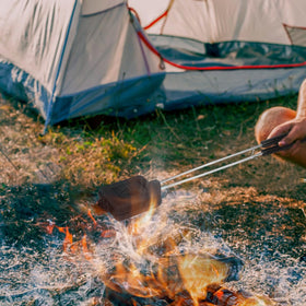 AILITOR camp pie cooker in action grilling sandwiches over a fire.