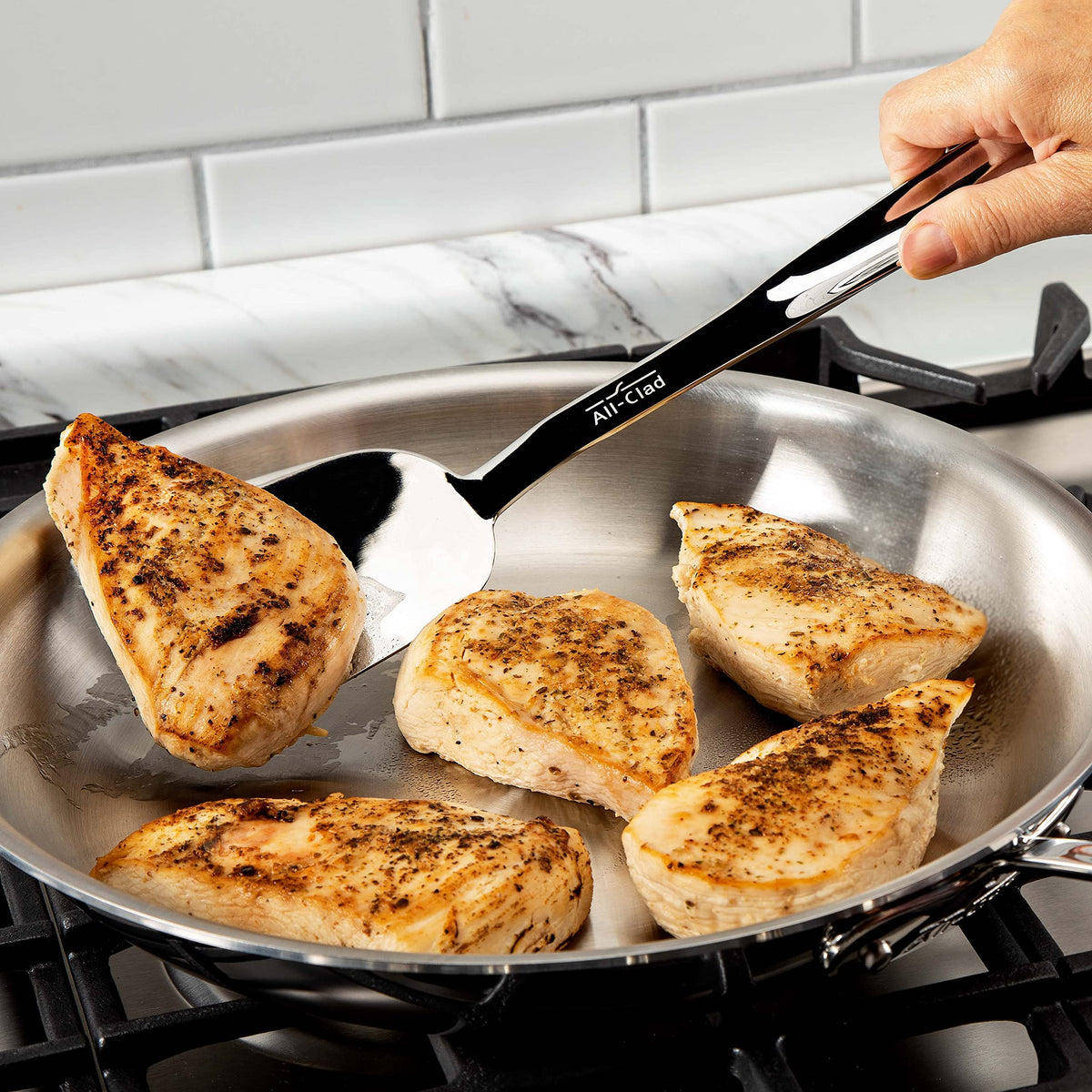 All-Clad turner with ergonomic handle offers comfortable grip for kitchen tasks.
