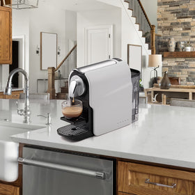 Beanglass espresso pod machine on a counter beside a mug for quick coffee.