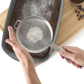 Calphalon Prime strainer close-up highlights fine mesh in action
