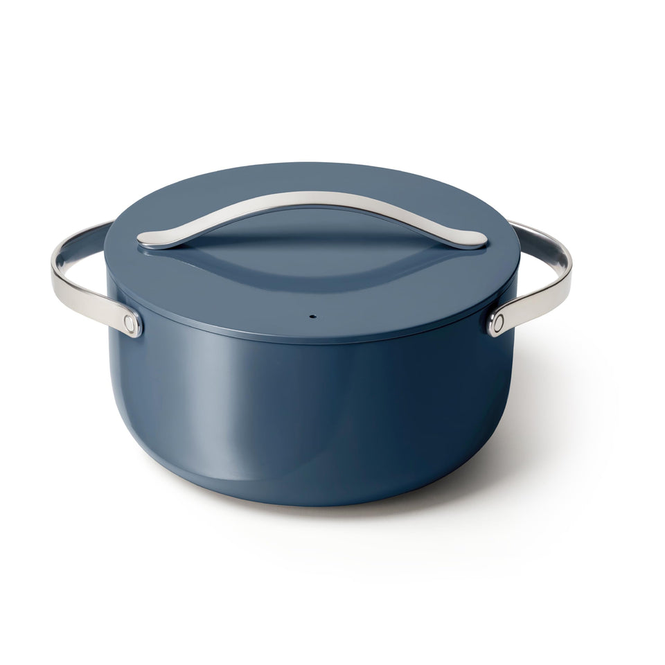 Caraway navy Dutch Oven with lid on stove, ideal for roasts and easy cleanup.