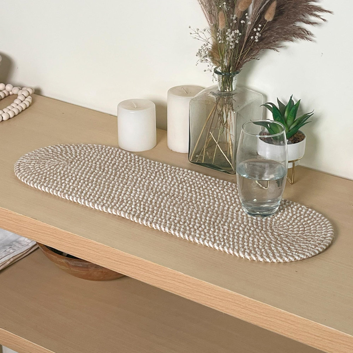 Chardin Home oval jute and cotton table runner in natural and white on a dining table.
