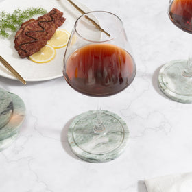 CHISELED ST DF SK wine glass on green marble coaster protecting the table.