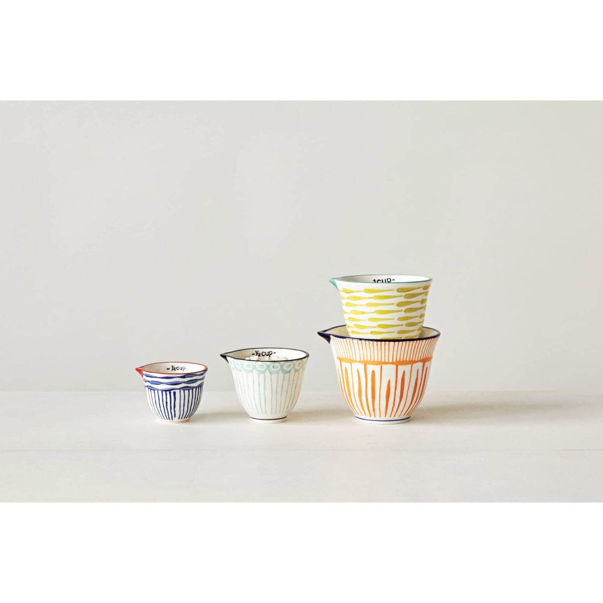 Creative Co-Op striped stoneware measuring cups in bold colors for precise measurements.