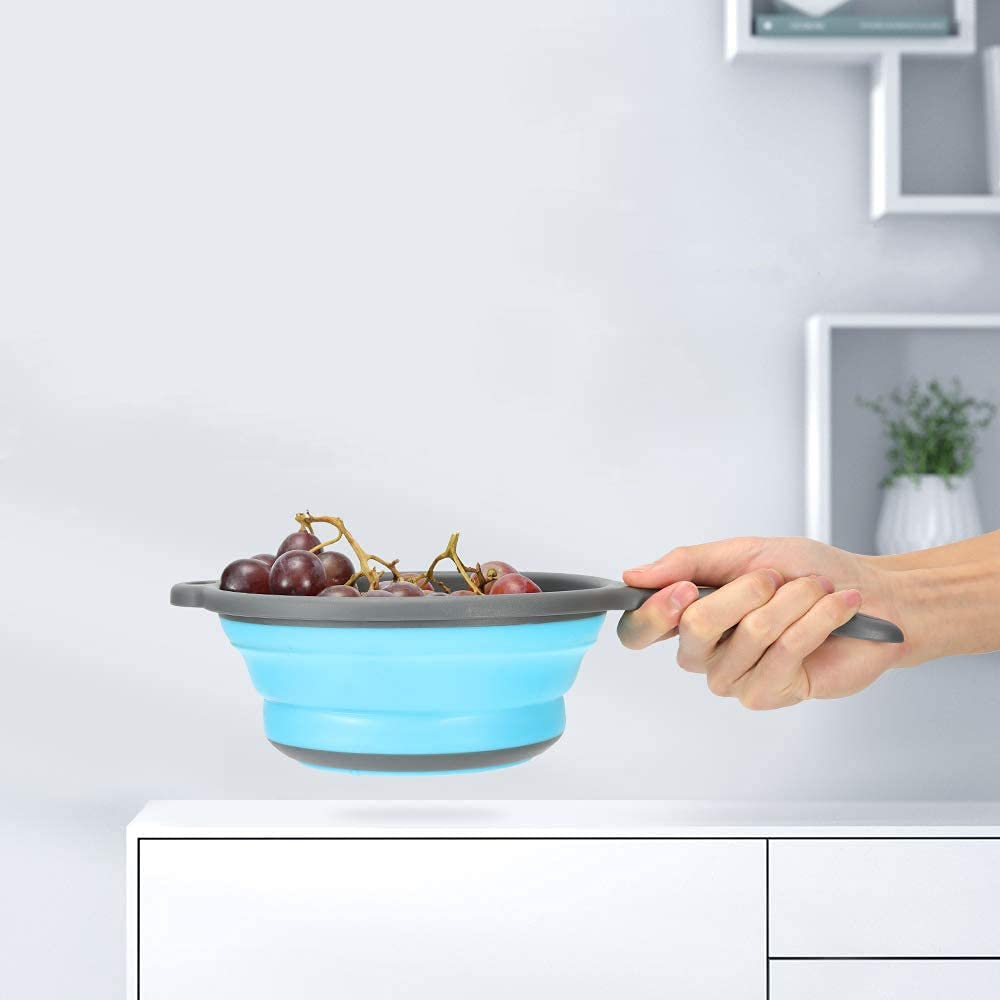 ddLUCK blue foldable colander with ergonomic base balances on the sink edge.