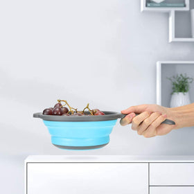 ddLUCK blue foldable colander with ergonomic base balances on the sink edge.