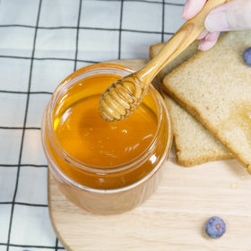 Exrmiae olive wood honey dipper in use, perfect on toast or yogurt.