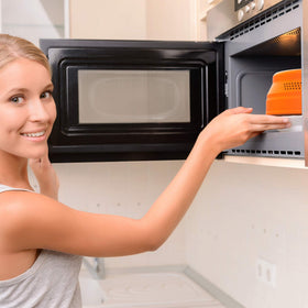 EZY ACTIVE orange collapsible cover protecting plates and bowls during microwaving.