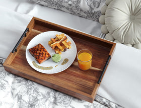 Fibogollo acacia wood tray on a coffee table in a living room.