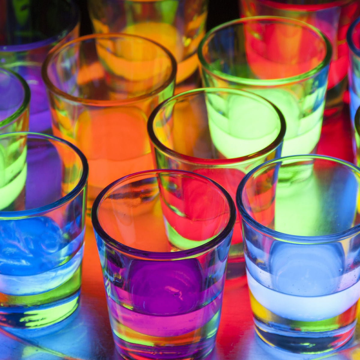 Glowing FLOMO—YDQ coaster illuminating a glass on a table.