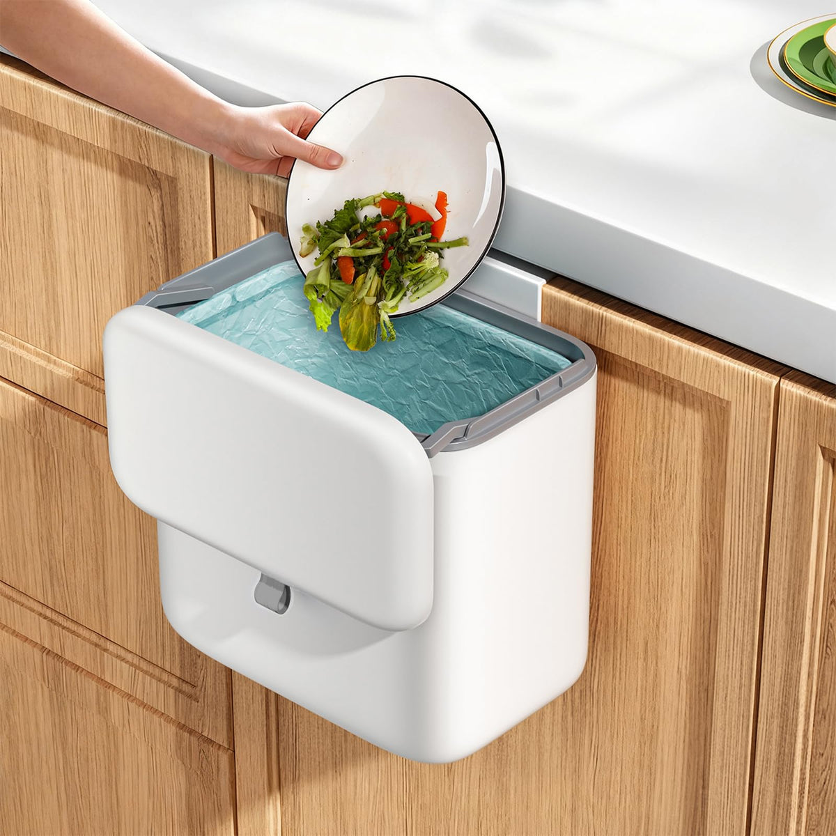 Gleynest compost bin with lid hanging on cabinet door for easy disposal