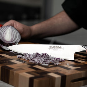 Global Knives in-action slicing vegetables on a cutting board.