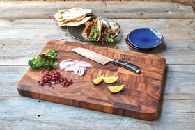 Ironwood Gourmet board in use for chopping vegetables on a busy kitchen counter.