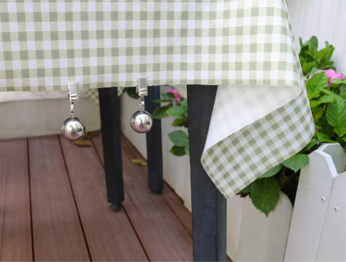 Iyulania tablecloth weights with clips securing cloths on a windy patio.