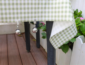 Iyulania tablecloth weights with clips securing cloths on a windy patio.