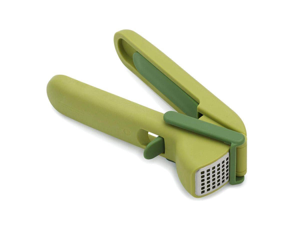 Joseph Joseph CleanForce garlic press with trigger-wiper in action for easy crushing