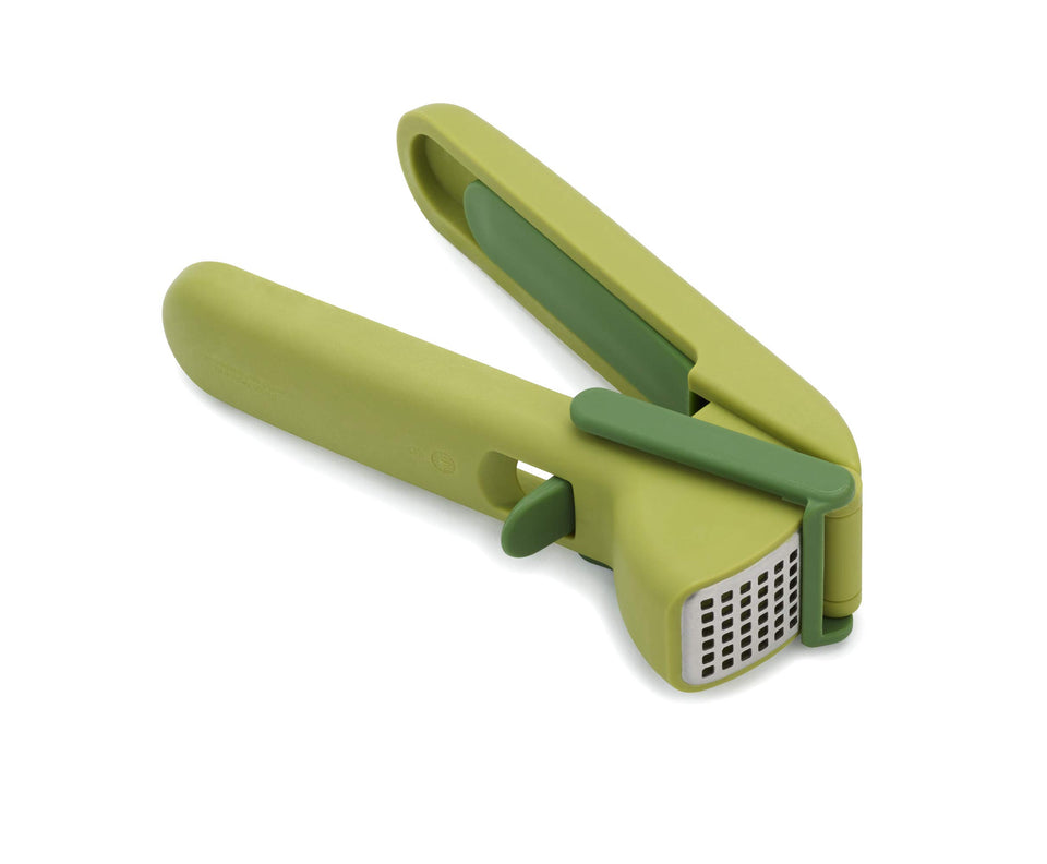 Joseph Joseph CleanForce garlic press with trigger-wiper in action for easy crushing