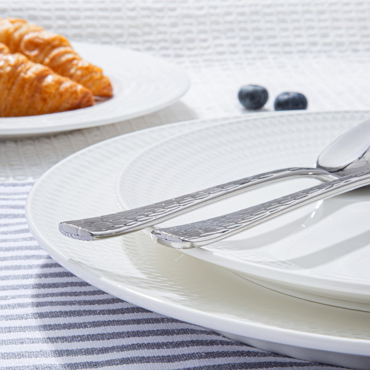 Kingstone mirror-finish hammered flatware reflecting light at table