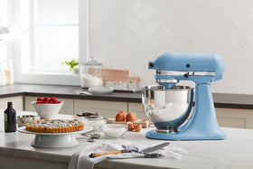 KitchenAid Artisan Tilt-Head Mixer in blue velvet highlighting hub-powered attachments option.