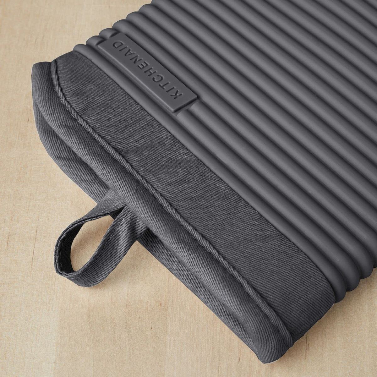 KitchenAid ribbed silicone oven mitt demonstrating textured grip for safe pan handling