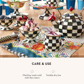 MACKENZIE-CHILDS dish towel against a black-and-white polka-dot backdrop.
