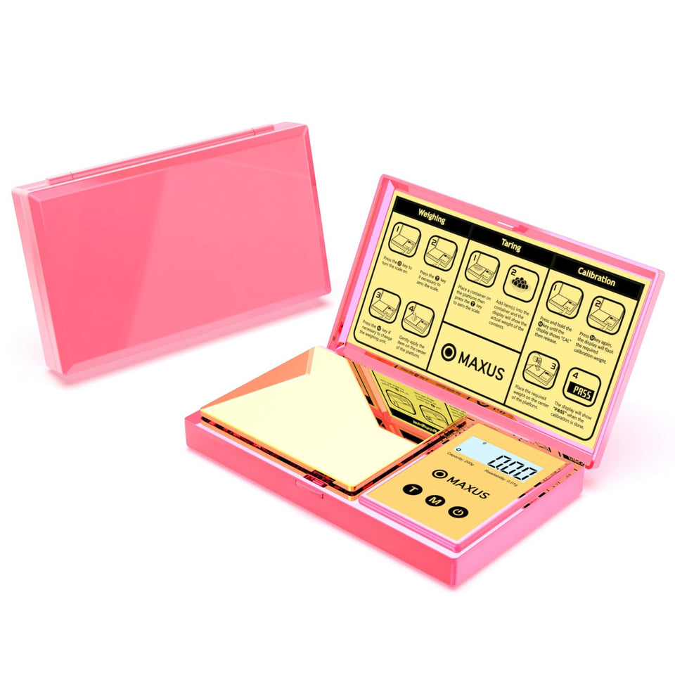 MAXUS digital gram scale with pink cover for precise 0.01 g readings of small items.