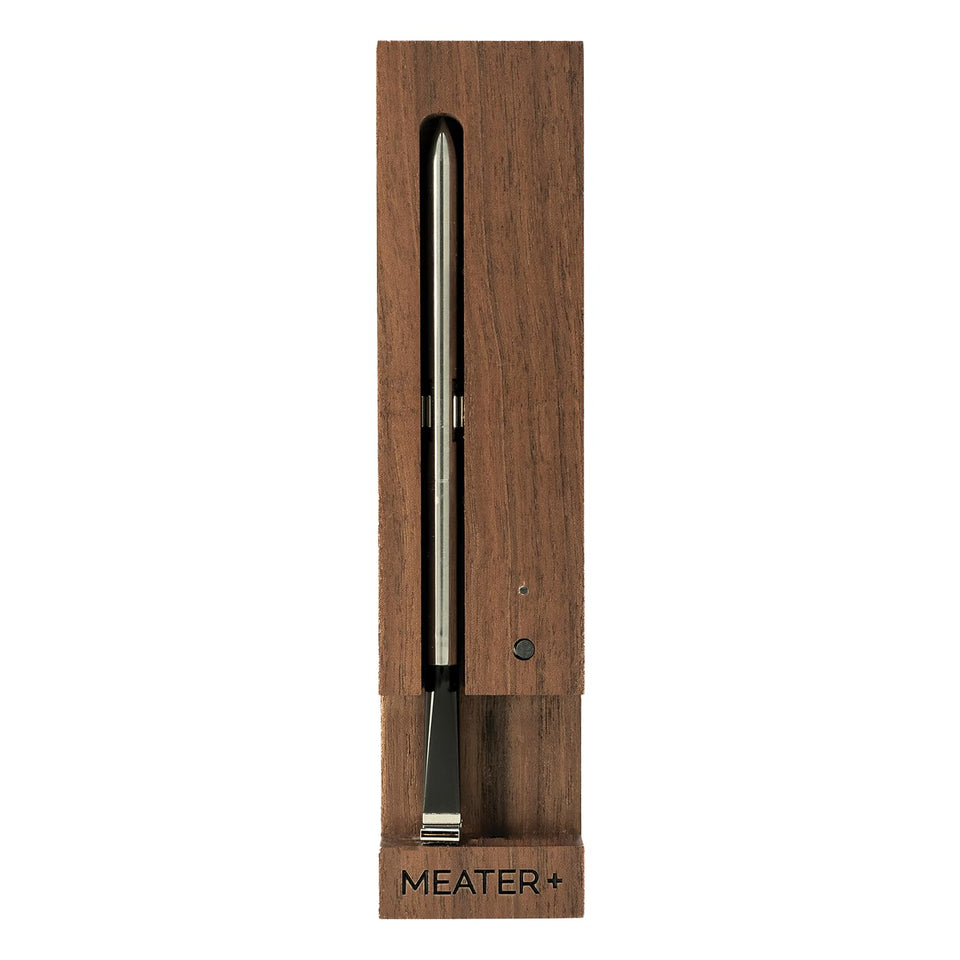 MEATER Plus walnut thermometer on charger enabling wireless monitoring of cooks.