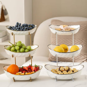 MEIGLQEA gold stand supporting a modern three-tier fruit display