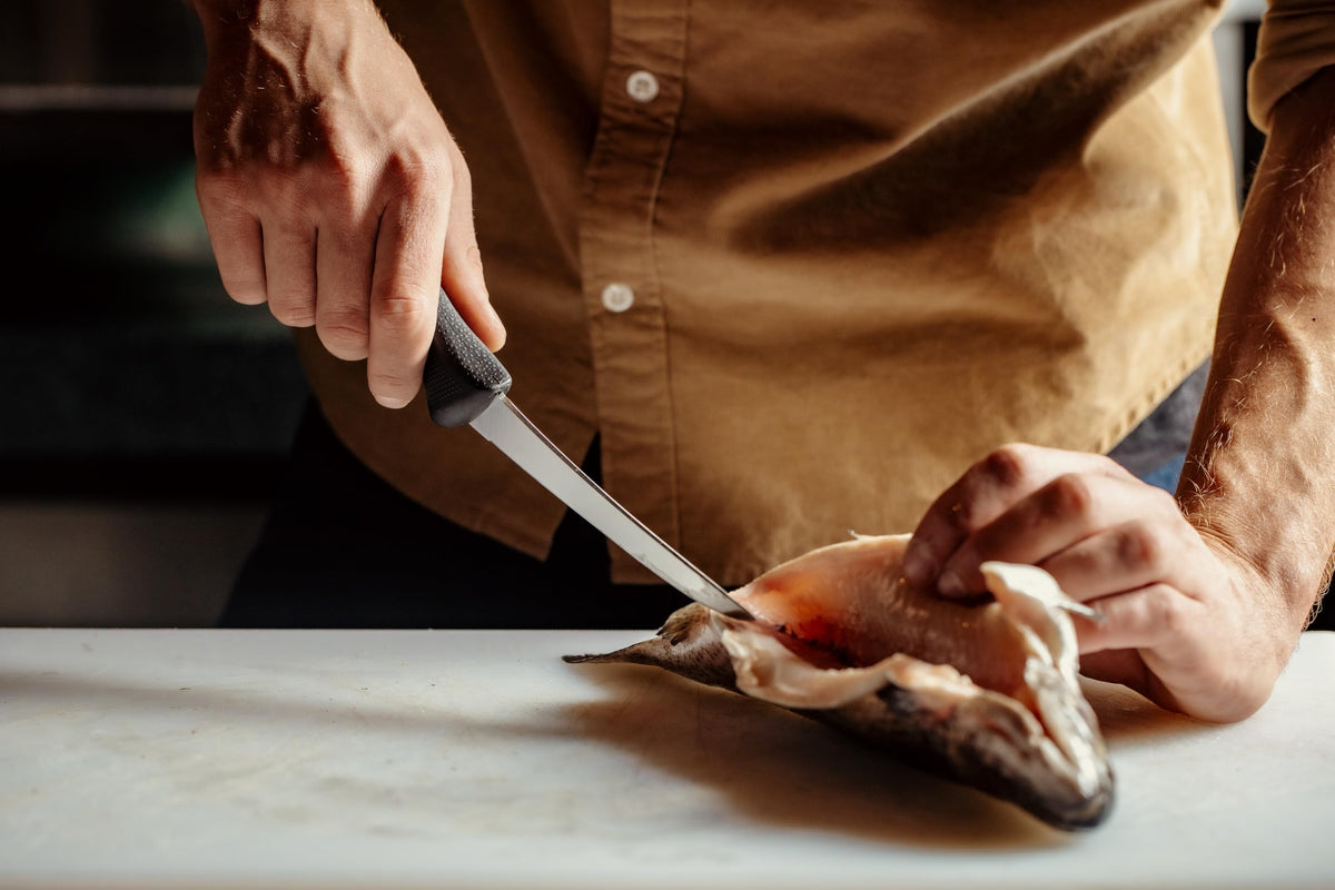 Mercer Culinary Millennia boning knife on cutting board for meat separation.