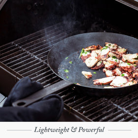Merten & Storck pan over campfire, ideal for outdoor searing.