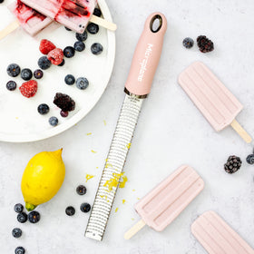 Microplane dusty rose zester hanging on magnetic strip for storage.