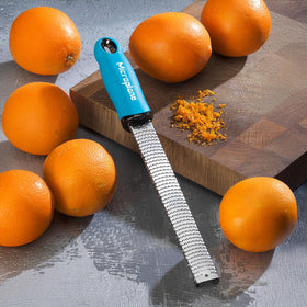 Microplane Premium Classic Turquoise zester shown being cleaned, dishwasher-safe