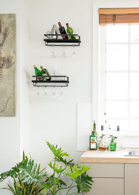Mkono floating shelves displaying bottles glasses and photos in a modern kitchen.