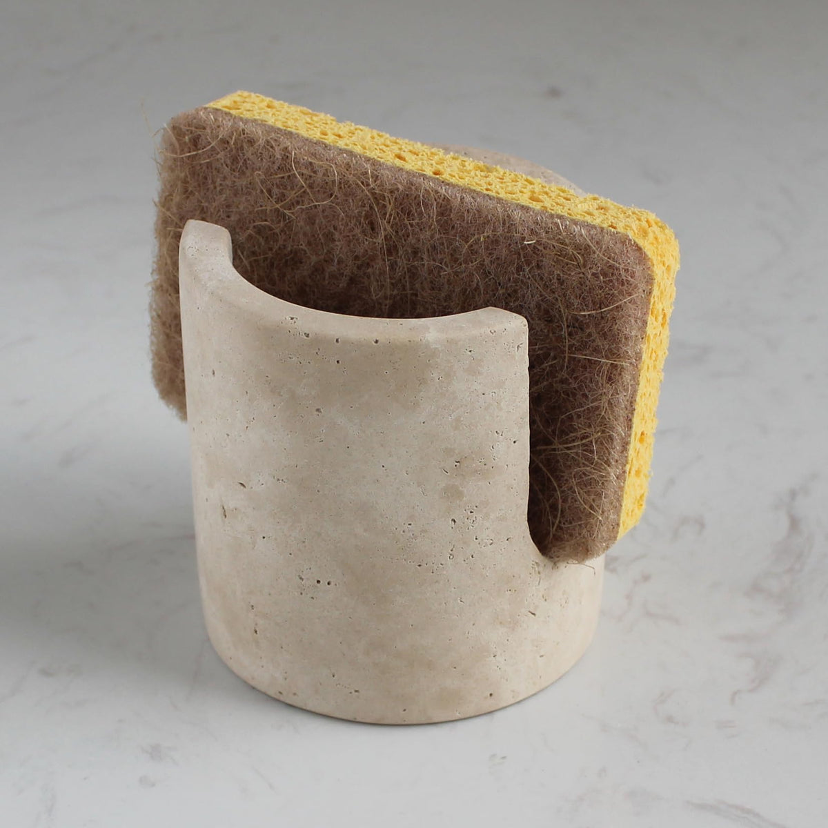Nawgnail travertine sponge holder in beige beside the sink, keeping counters tidy.