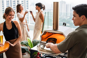 Ooni Grizzler Pan over open fire for outdoor cooking sessions.