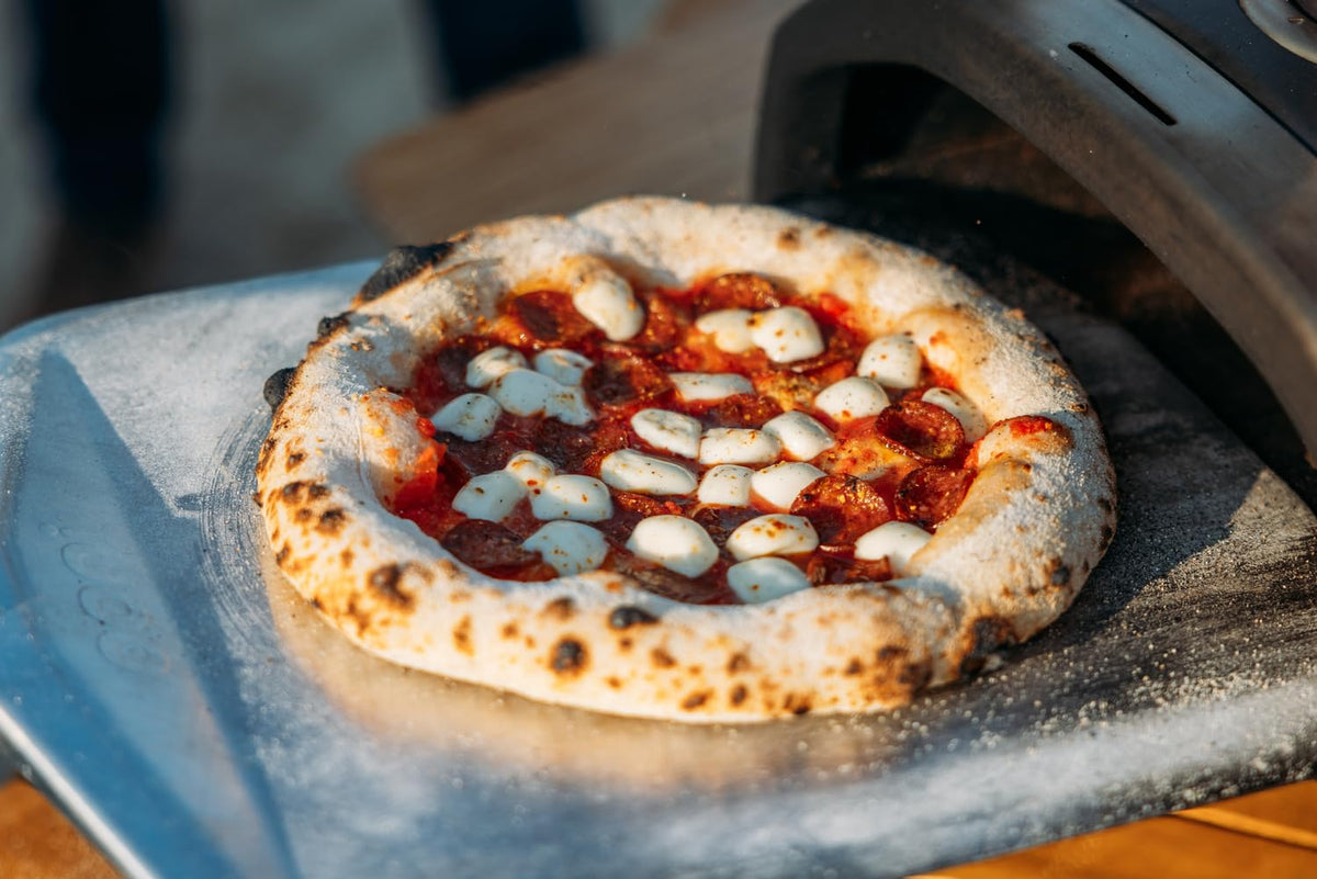 Ooni long-handle peel enables precise placement from hot ovens