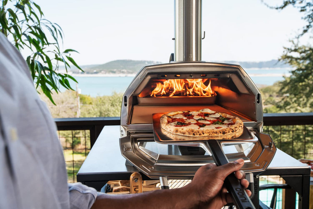 Ooni pizza peel launching a pizza into the oven with ease