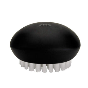 OXO Good Grips Vegetable Brush handle detail shows a flexible, non-slip grip in action.