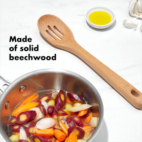 OXO Good Grips wooden slotted spoon draining liquids during cooking.