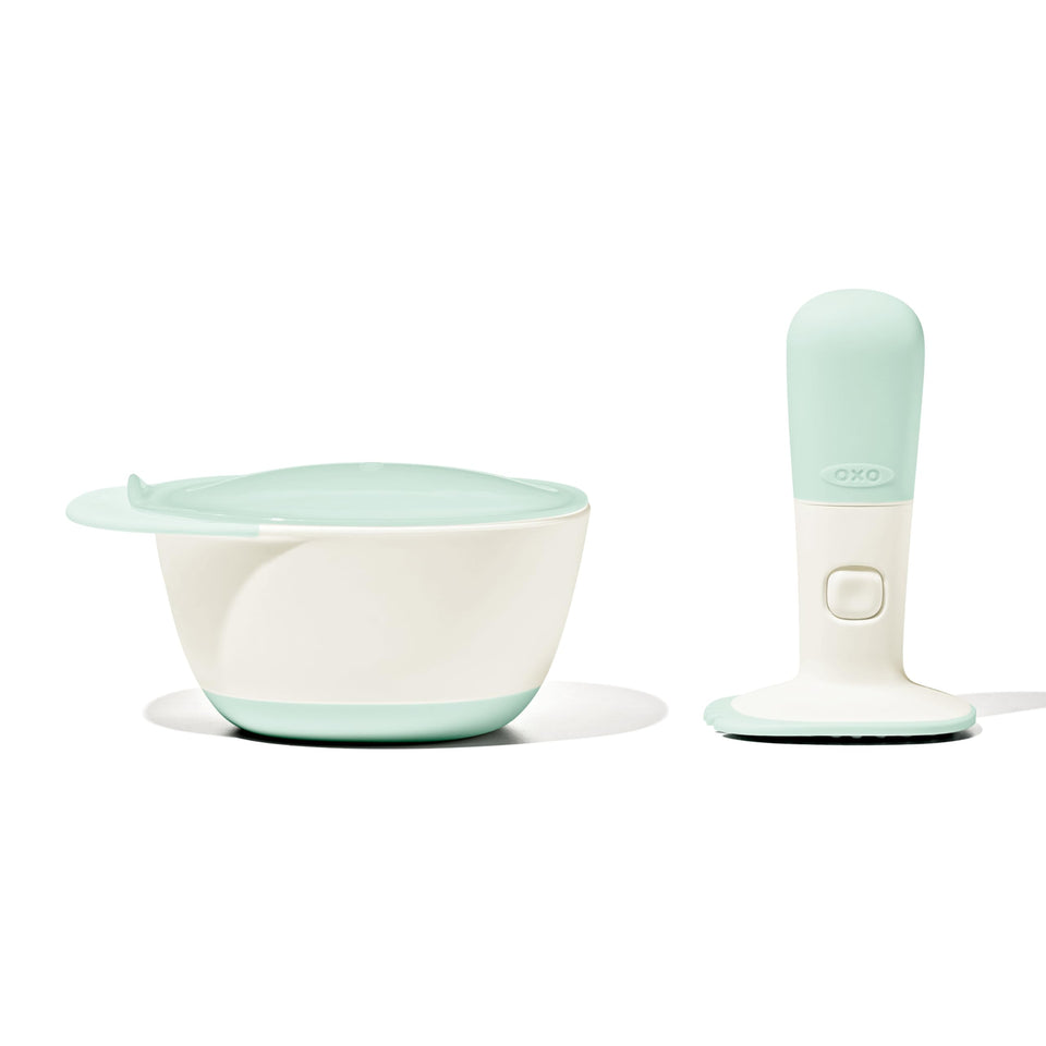 OXO Tot Food Masher Opal in use, mashing soft fruits for baby purée