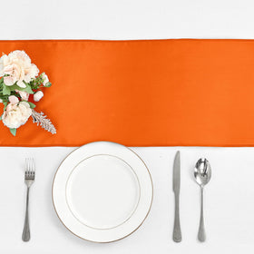 Pufogu orange satin table runner draped over banquet table creates a focal glow