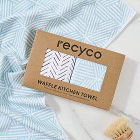 RECYCO kitchen towel in action cleans spills on dishes and counters.