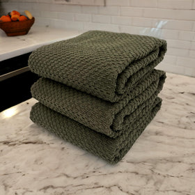 Oversized Serafina Home olive green towels drying spills and cleaning surfaces efficiently.