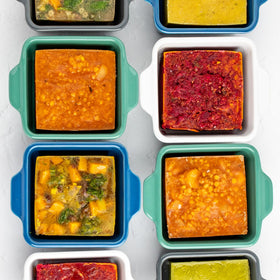 Souper Cubes silicone cover shown on cranberry stoneware dish for storage.