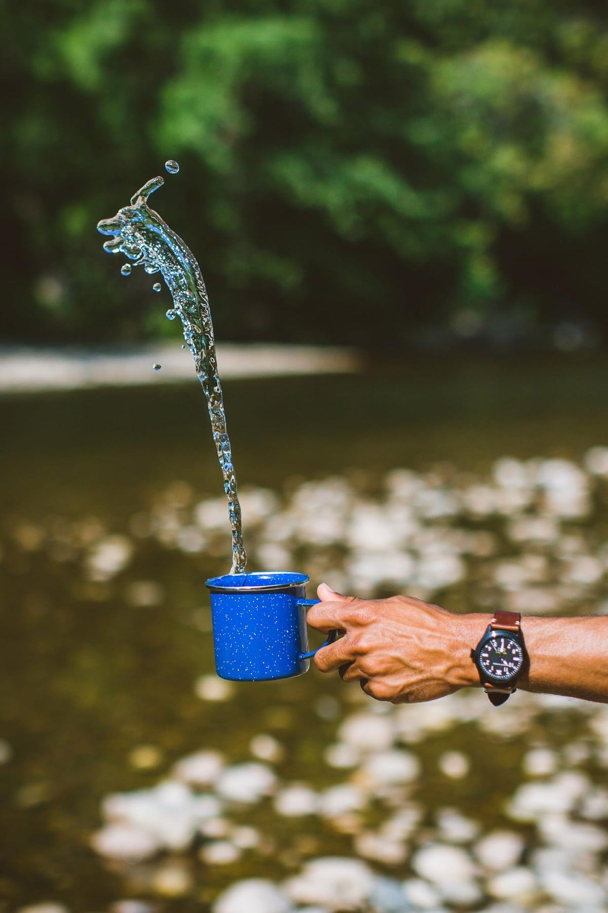 Stansport blue enamel mug with hot coffee steam outdoors.