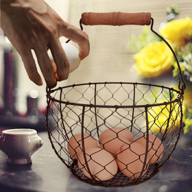 TAIANLE round metal egg basket neatly displays fresh eggs on the kitchen counter.