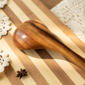 TEZZ natural acacia utensils against light kitchen background.