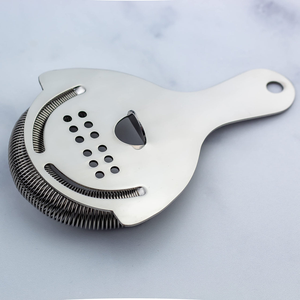 The Art of Craft Hawthorne Strainer being washed, dishwasher-safe for easy cleanup.