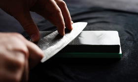 Close-up applying Thirteen Chefs honing oil to a carbon steel blade.