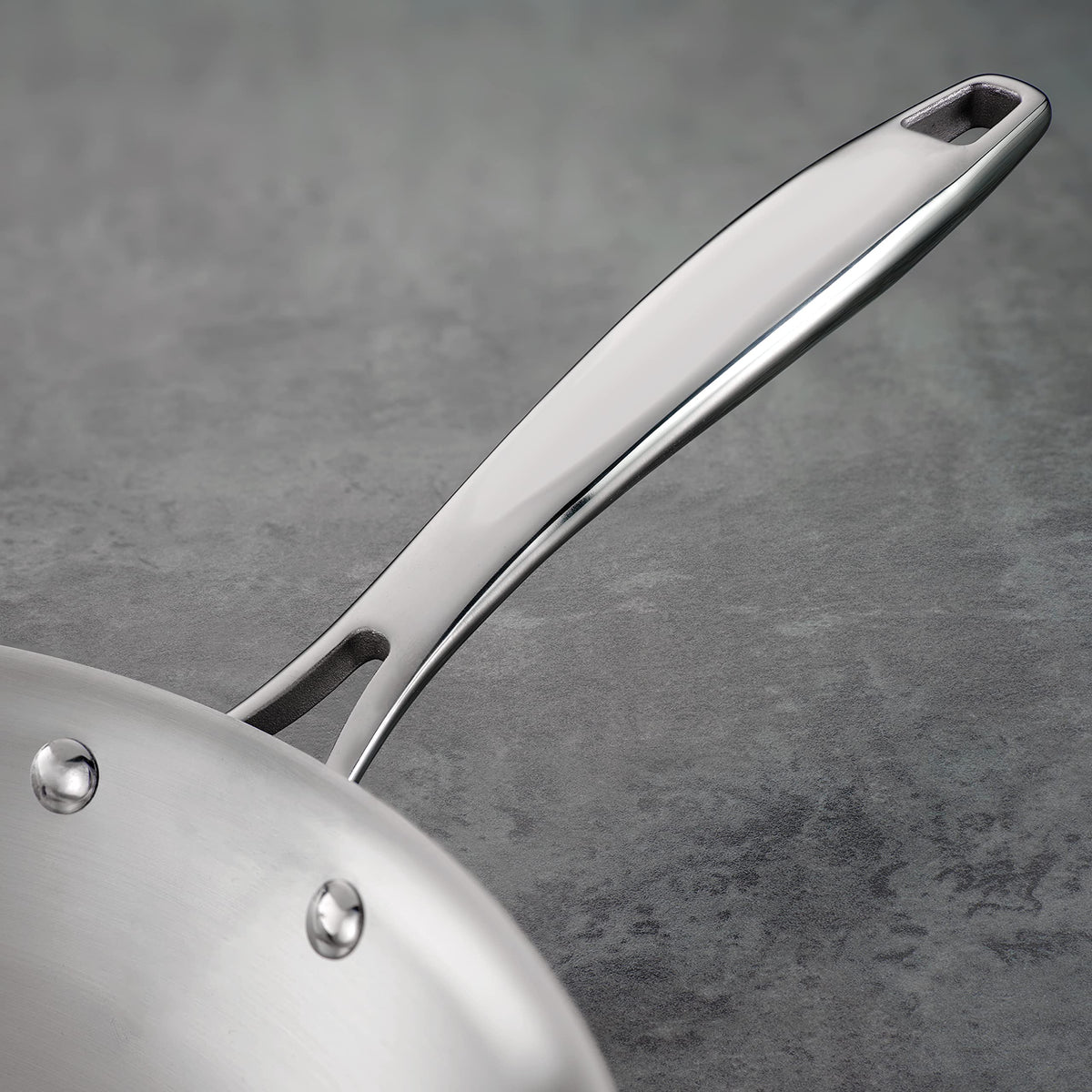 Ergonomic riveted handle on the Tramontina tri-ply fry pan for secure grip.